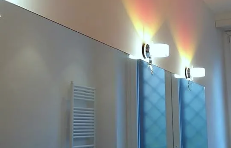 Bagno ristrutturato con applique a parete, rivestimento a mosaico e termoarredo