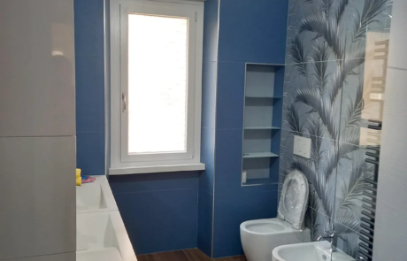 Bagno ristrutturato con pareti blu, carta da parati decorativa e sanitari sospesi