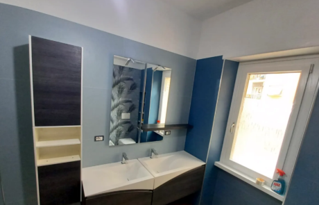 Bagno ristrutturato con pareti blu, doppio lavabo e mobile sospeso