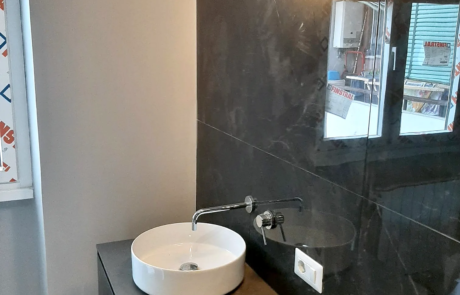 Bagno ristrutturato con lavabo da appoggio tondo, rubinetto a parete e rivestimento scuro