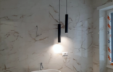 Ristrutturazione bagno con rivestimento effetto marmo, lavabo da appoggio e lampade a sospensione