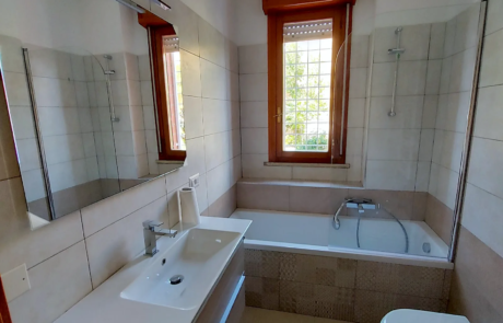 Bagno ristrutturato con vasca, mobile lavabo sospeso e specchio contenitore