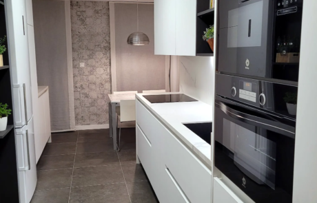 Cucina bianca con colonne forno e pavimento in gres scuro in un appartamento ristrutturato