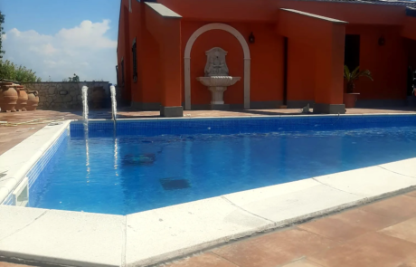 Piscina ristrutturata con bordo in pietra chiara e pavimentazione esterna in cotto