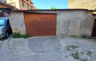 Prima dei lavori: vecchio garage con portone in ferro da trasformare in locale