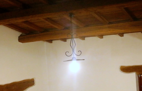 Soffitto con travi in legno a vista in un ambiente ristrutturato con pareti chiare